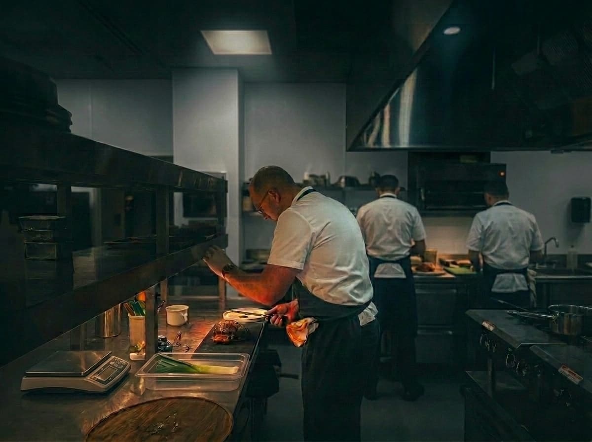 Michelin-trained ABLTY chefs plating performance meals on a dark kitchen line during late-night service